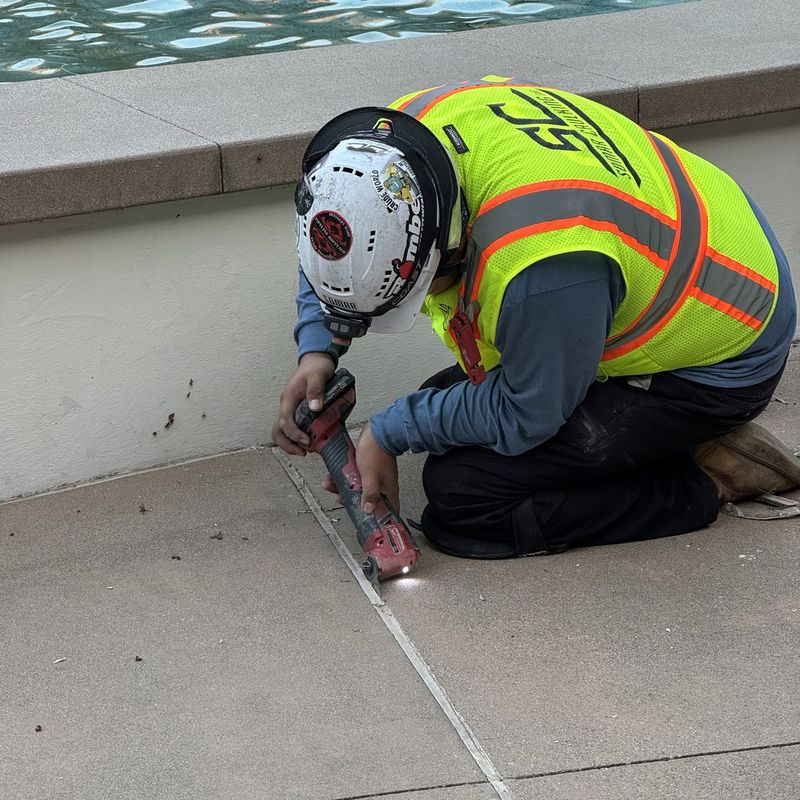 Somar Caulking crew member cutting failed sealant out of a plaza joint with an oscillating tool